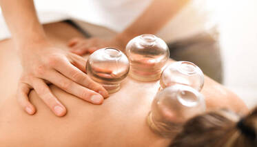 Detail of a woman therapist hands giving cupping treatment on back.