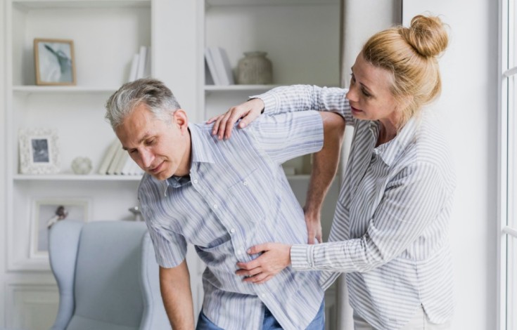 Person hunched over in pain, holding their lower back